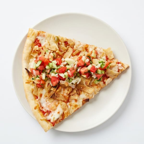 A slice of pizza with cheese, tortilla strips, and a fresh salsa topping on a white plate.
